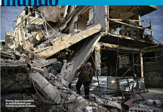  ??  ?? Homem observa escombros de edifício alvejado pelo Exército na cidade de Douma