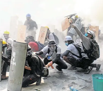  ?? PHOTO: REUTERS ?? Under attack: Protesters take cover as they clash with riot police officers during a protest against the military coup in Yangon, Myanmar.