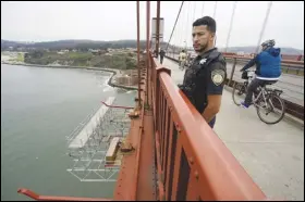  ?? ASSOCIATED PRESS FILES ?? Patrol officer Nicolas Serrano looks out at a suicide barrier under constructi­on below the Golden Gate Bridge in San Francisco, last year. The lead contractor in charge of building a suicide prevention net on the bridge that is already years behind schedule says it will cost about $400 million.