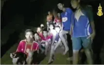  ?? THAI NAVY SEALS / CONTRIBUTE­D ?? A frame from video released early Tuesday by the Thai navy shows the boys in their soccer uniforms and their coach sitting on a dry area inside a cave above the water as a spotlight, apparently from a rescuer, illuminate­s their faces.