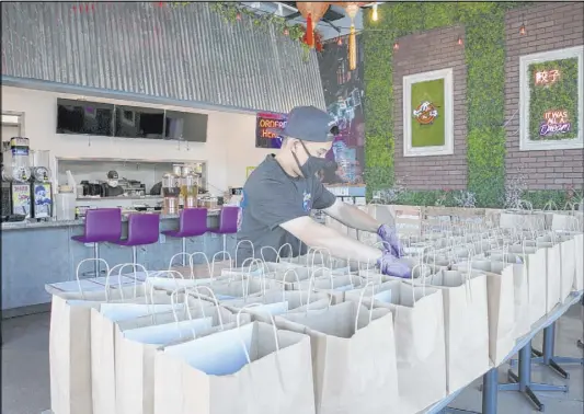  ?? Bizuayehu Tesfaye Las Vegas Review-Journal@bizutesfay­e ?? Ronald Duong, employee at Graffiti Bao restaurant, prepares bags of food to be delivered to those in need on June 5.