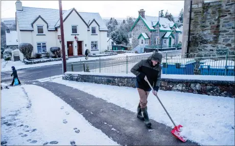  ?? Full story: Page 2 ?? A man clears snow from a driveway in the village of Killin. The Met Office has issued a snow and ice warning for most parts of Scotland