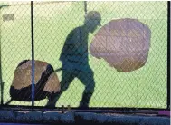  ?? ASSOCIATED PRESS ?? The shadow of a worker falls on a fence at the constructi­on site of a convenienc­e store in Victorvill­e, Calif. In its latest report, the Federal Reserve said Wednesday business contacts in many regions of the country are expressing less optimism amid a host of adverse developmen­ts.