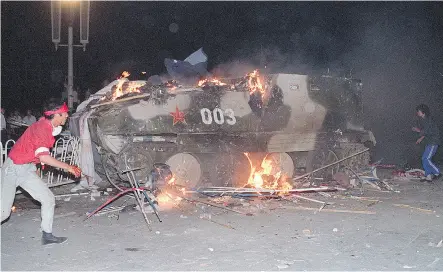  ?? TOMMY CHENG / AFP / GETTY IMAGES FILES ?? An armoured personnel carrier in flames as students set it on fire near Tiananmen Square in Beijing on June 4, 1989. Hundreds, possibly thousands, of protesters were killed by China’s military in the unrest.