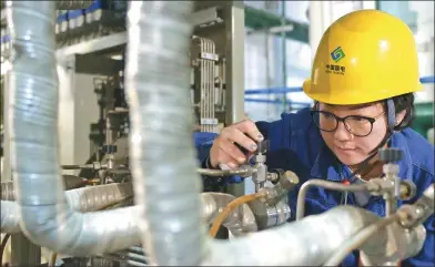  ?? XINHUA ?? A technician of China Guodian Corp checks facilities in Lanzhou, capital of Gansu province. The merger between China Guodian Corp and Shenhua Group has been approved.