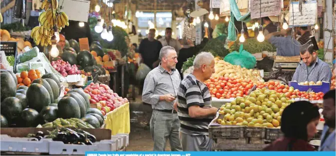  ?? — AFP ?? AMMAN: People buy fruits and vegetables at a market in downtown Amman.