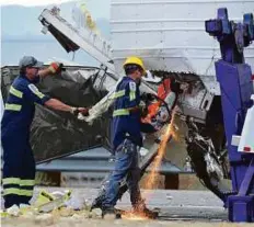  ??  ?? Workers remove wreckage from a semi-truck that was hit by a tour bus on Interstate 10 just west of the Indian Canyon Drive off-ramp, in Desert Hot Springs, California.