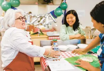  ?? SHAFKAT ANOWAR/DALLAS MORNING NEWS PHOTOS ?? Terri Heard, left, jokes with the women in the monthly cooking class she teaches for Burmese refugees at HHM Health in Dallas.