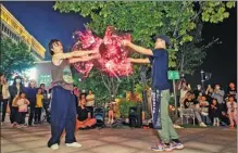  ??  ?? Two Chinese street artists juggle and dance with illuminate­d poi during the outdoor art festival in Beijing earlier this month.