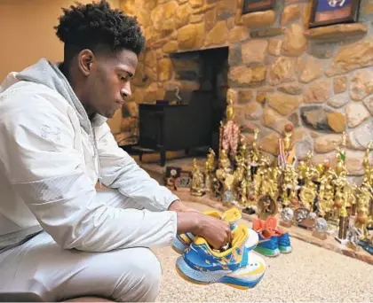  ?? KARL MERTON FERRON/BALTIMORE SUN ?? Poly senior basketball player Rahim “Rah” Ali holds shoes bearing the name of his late mother, Chantille Tiffany Land-Ali.