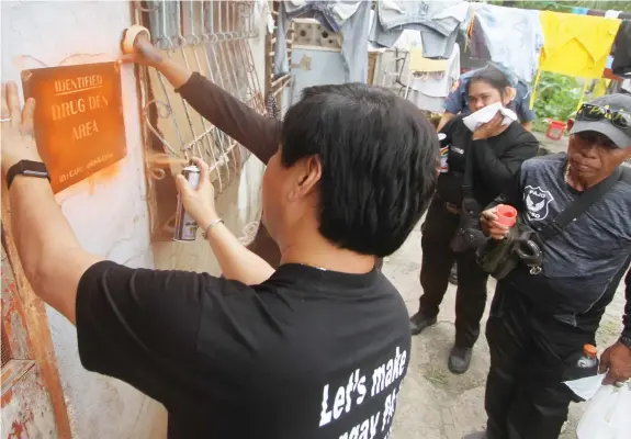  ?? JOY TORREJOS ?? Barangay chairman Junard “Ahong” Chan of Pajo, Lapu-Lapu City marks the door of a house in Sitio Kamanggaha­n as part of his shame campaign against drug suspects in his barangay.