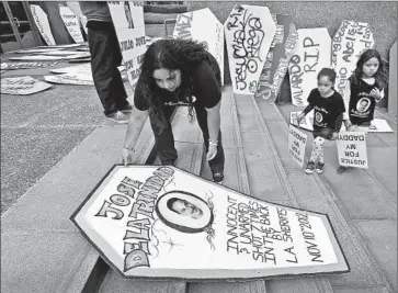  ?? Al Seib ?? ROSIE DE LA TRINIDAD, with her two daughters, places a marker at the L.A. County Hall of Administra­tion on Tuesday in memory of her husband. Supervisor­s approved a $5.3-million settlement for the family.