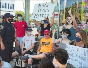  ?? JOE WOJTAS/THE DAY ?? Stonington Officer Theresa Hersh, far left, mediates discussion Thursday between protesters and a Trump supporter in Mystic. Visit theday.com for a video of the officers.