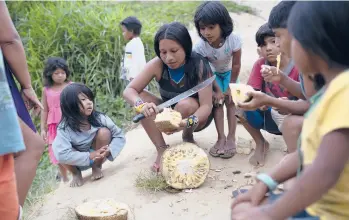  ?? SILVIA IZQUIERDO/AP 2020 ?? A woman cuts jackfruit Nov. 30 in the Sapukai village near Angra dos Reis, Brazil. To the extent Brazilians consume jackfruit, it’s mostly eaten ripe. The fruit, which originated in India, tastes like a combinatio­n of pear and banana.