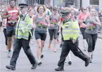  ??  ?? Police officers react as they attempt to cross a road through the path of runners during the Vitality London 10km run in central London. — AFP