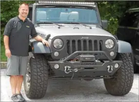  ?? PETE BANNAN — DIGITAL FIRST MEDIA ?? John Stewart, president of Quadratec, is shown at the company’s headquarte­rs in West Goshen with a 2014 Jeep Wrangler.