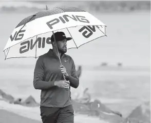  ?? Marcio Jose Sanchez, The Associated Press ?? Tony Finau carries an umbrella in the rain on the 18th fairway during the third round of The American Express golf tournament on Saturday.