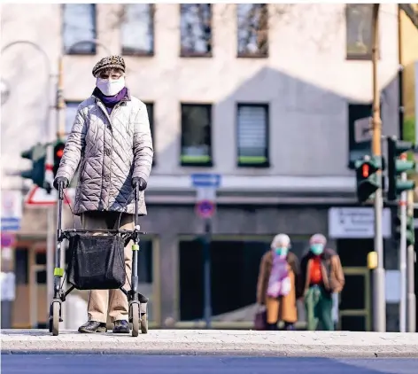  ?? FOTO: DPA ?? Eine Seniorin auf der Breite Straße in Köln mit Atemschutz­maske.