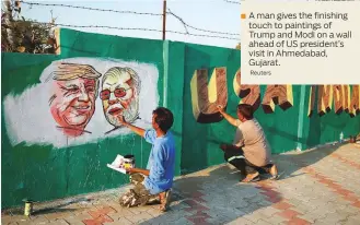  ?? Reuters ?? A man gives the finishing touch to paintings of Trump and Modi on a wall ahead of US president’s visit in Ahmedabad, Gujarat.