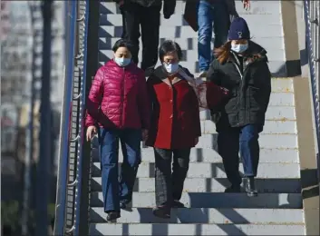  ?? AP photo ?? People wearing face masks to help curb the spread of the coronaviru­s walk down a pedestrian overhead bridge in Beijing on Sunday.