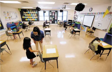  ?? PHOTOS BY LUIS SÁNCHEZ SATURNO/THE NEW MEXICAN ?? Evelyn Rivera, first grade teacher at Santo Niño Regional Catholic School, works with Leila Quintana, 6, in the classroom Tuesday. Santo Niño, where classes started late last month, chose to begin the year under what it calls a ‘community choice’ model in which students can either attend class or take part online. Of the school’s 135 students, 35 are using the virtual option.