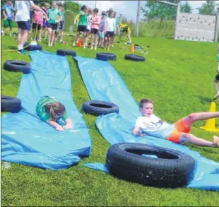  ??  ?? Children at Mersham Primary School enjoy a cool ride on the water slide; while Liam Burgess, right, cools down with a wet sponge