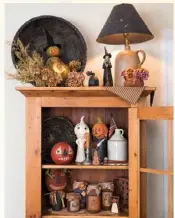  ??  ?? Left: Julie framed a pumpkin figure using a basket turned on its side atop a simple wooden cabinet in her dining room, filling in around it with dried florals. On the shelves below, other fanciful folkart pieces cavort amid crockery and faux preserves.