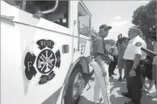  ?? Associated Press ?? Texas Rangers’ Lance Berkman, left, is given a tour of a Ford Commercial Pumper Fire Truck by Bill McQuatters, Arlington Fire Department Battalion Chief 3, before a baseball game against the Seattle Mariners on Wednesday in Arlington, Texas. Berkman,...