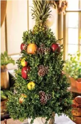  ??  ?? Far left: A fresh boxwood and apple arrangemen­t, like this one in the garden room, will last throughout the holiday season if you regularly spritz its leaves with water.