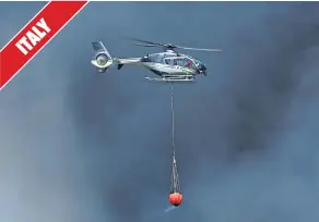  ??  ?? Dense smoke engulfs a helicopter dropping water in a district of Rome