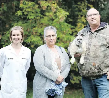  ?? TARYN RIEMER/WESTERN COLLEGE OF VETERINARY MEDICINE ?? Norma and Kelly Tait were happily reunited with their dog, Toby, after Dr. Danielle Zwueste, left, removed a large tumour from the top of his skull.