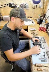  ?? NWA Democrat-Gazette/DAVID GOTTSCHALK ?? Hunter Villines, a gunsmith at Wilson Combat, disassembl­es a Glock handgun at the company’s workshop in Berryville.