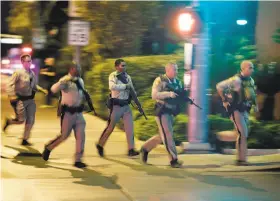  ?? John Locher / Associated Press 2017 ?? Law officers run toward the scene of the Oct. 1, 2017, shooting near the Mandalay Bay resort in Las Vegas that killed 58 people and injured hundreds.