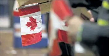  ?? POSTMEDIA FILE PHOTO ?? A new citizen holds a Canadian flag during a citizenshi­p ceremony held in Edmonton. A 2014 government report, recently released, outlines areas where Canadian immigrants have increasing struggles.