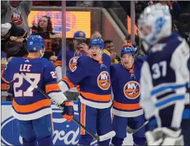  ?? AP PHOTO/FRANK FRANKLIN II ?? New York Islanders’ Hudson Fasching (20) celebrates with teammates Mathew Barzal (13) and Anders Lee (27) after scoring a goal as Winnipeg Jets goaltender Connor Hellebuyck (37) looks away during the second period of an NHL hockey game Saturday, March 23, 2024, in Elmont, N.Y.