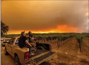  ?? (AP/Noah Berger) ?? Charles Chavira (left) and Thomas Henney watch smoke from wildfires spread over a vineyard near Healdsburg in Sonoma County, Calif., on Aug. 20.