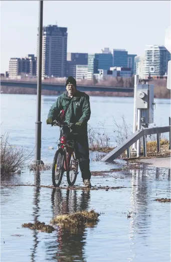  ?? ERROL McGIHON ?? A cyclist stops at the intersecti­on of rue Jacques-Cartier and rue des Montgolfiè­res in Gatineau, which was closed due to flooding on Monday. Water levels are expected to peak by Saturday.