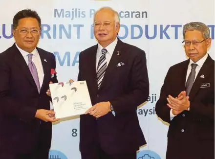  ?? PIC BY MOHD FADLI HAMZAH ?? Prime Minister Datuk Seri Najib Razak receiving a copy of the Malaysia Productivi­ty Blueprint from Minister in the Prime Minister’s Department Datuk Seri Abdul Rahman Dahlan at its launch in Putrajaya yesterday. With them is Internatio­nal Trade and...