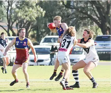  ?? Photograph­s by AMANDA EMARY ?? Dusties midfielder Kane Oldham is set upon by Nar Nar Goon players Brendan Hermann and Eamon Trigg as a teammate watches on.