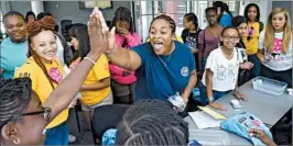  ?? JAHI CHIKWENDIU/WASHINGTON POST ?? Ann-Audrey Ezi, left, gets a high-five from Amber Smith-St. Louis after Ezi's floating aluminum foil structure won a foil boat test at a summer camp for girls called FOCUS.