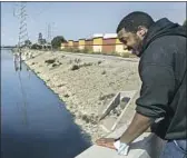  ?? Mel Melcon Los Angeles Times ?? RICHARD MOOTRY, who said he works across the street at a Verizon store, looks out at the channel, which has had a buildup of hydrogen sulfide.