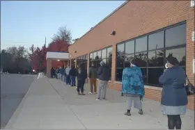  ?? ANNE RUNKLE — MEDIANEWS GROUP ?? Voters line up outside Farmington High School just a few minutes after the polls opened Tuesday. On the other side of theparking lot, a Farmington Public Safety Department officer sat in a patrol car. Police in several Oakland County police department­s said they were prepared for unrest at the polls, but also wanted to keep their distance so they didn’t intimidate voters.