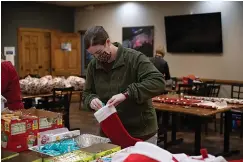  ?? Staff photo by Kelsi Brinkmeyer ?? ■ Kimi Ryan, member and employee at Church on the Rock, stuffs a stocking with candy and snacks on Wednesday for the church’s Christmas Community Outreach.