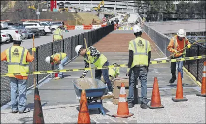  ?? CURTIS COMPTON / CCOMPTON@AJC.COM ?? Constructi­on workers scramble to complete the pedestrian bridge from the parking lots of the Cobb Galleria over I-285 to SunTrust Park on March 23. Projects across the state have highway contractor­s scrambling to find workers.