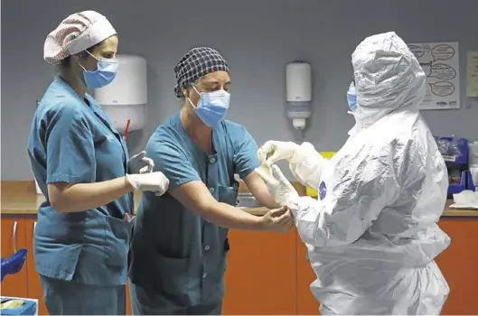  ?? JAIME GALINDO ?? Unos sanitarios, colocándos­e los equipos de protección en el hospital Miguel Servet de Zaragoza.