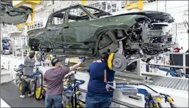  ?? Brian Cassella/Chicago Tribune/TnS ?? Workers lower an R1T truck body onto a chassis in the assembly line, April 11, 2022, at the Rivian electric vehicle plant in Normal, Illinois.
