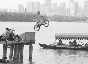  ?? PROVIDED TO CHINA DAILY ?? A man riding a bicycle tries to jump over part of the Donghu Lake in Wuhan, Hubei province.