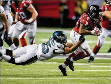  ?? CURTIS COMPTON / CCOMPTON@AJC.COM ?? Falcons running back Devonta Freeman (right) tries to escape the grasp of Eagles linebacker Mychal Kendricks during a 2015 game in Atlanta. Slowing down Freeman is one of the keys for the Eagles.