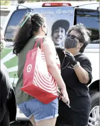  ?? The Maui News/MATTHEW THAYER photos ?? Evie Chargualaf (right) gets a hug from niece Shanelle Domingo before the start of Saturday’s memorial ride.