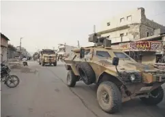  ??  ?? 0 A Turkish military convoy passes through the town of Atareb